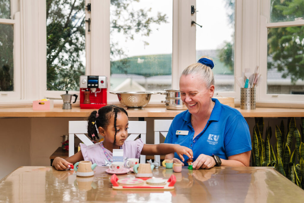 KU Briar Cottage childcare educator and a child having a tea party