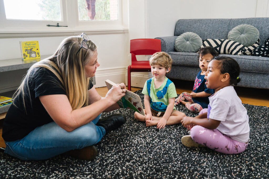 KU Briar Cottage childcare educator reading a story to some children