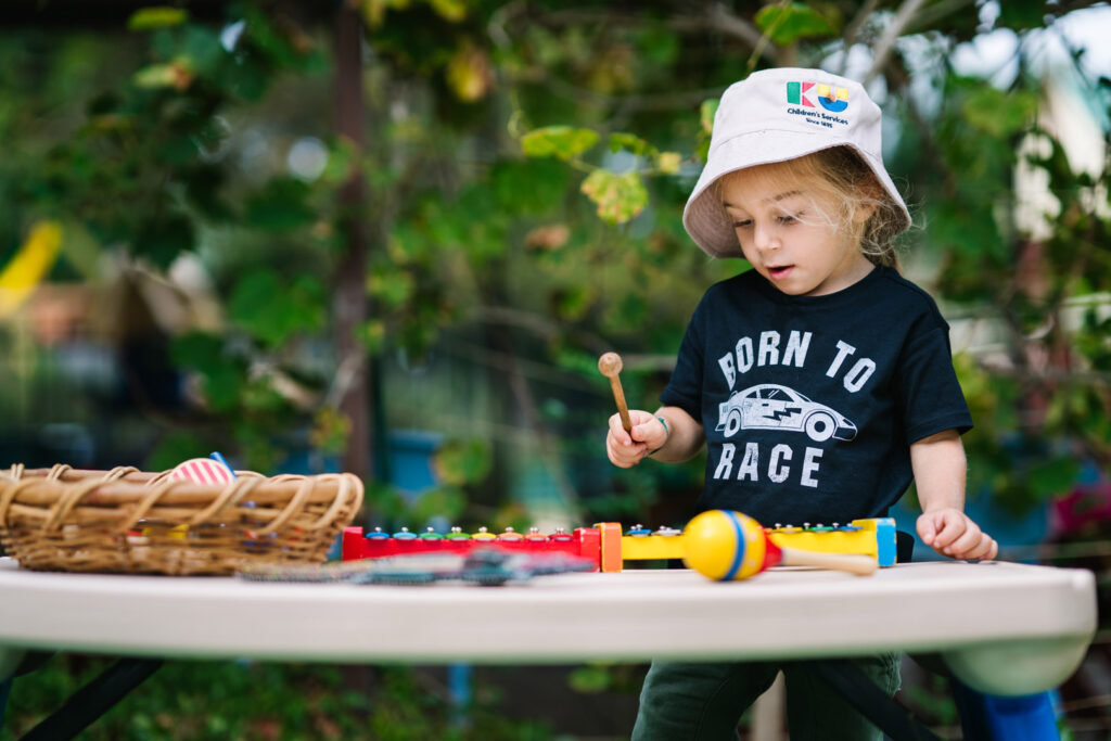 Child playing a xylophone at KU Briar Cottage childcare