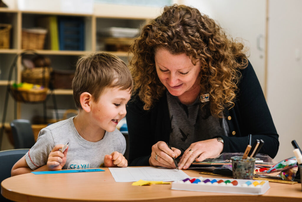 KU Phoenix childcare educator doing some writing with a child