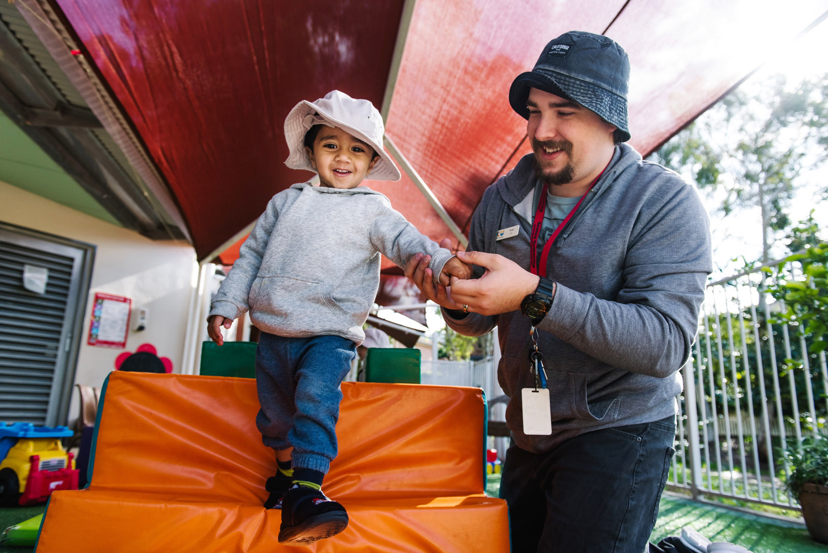 KU Village Green childcare educator assisting a child on the equipment