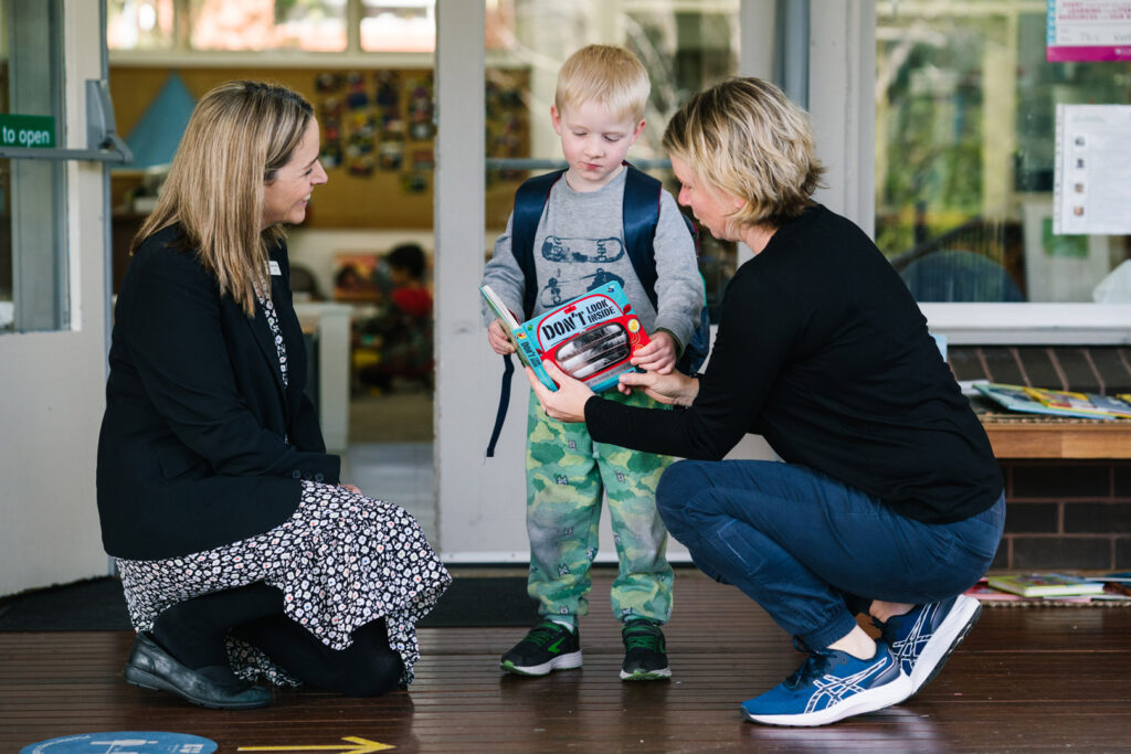 KU Berowra childcare educators reading a book with a child