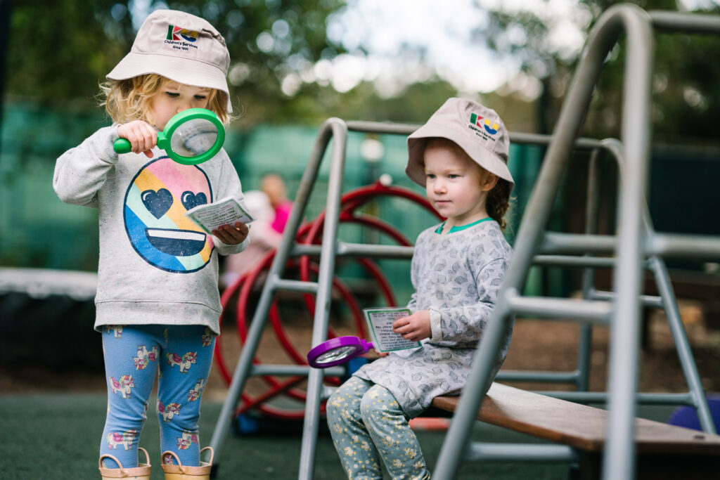 Children using magnifying glasses to study objects at KU Berowra childcare