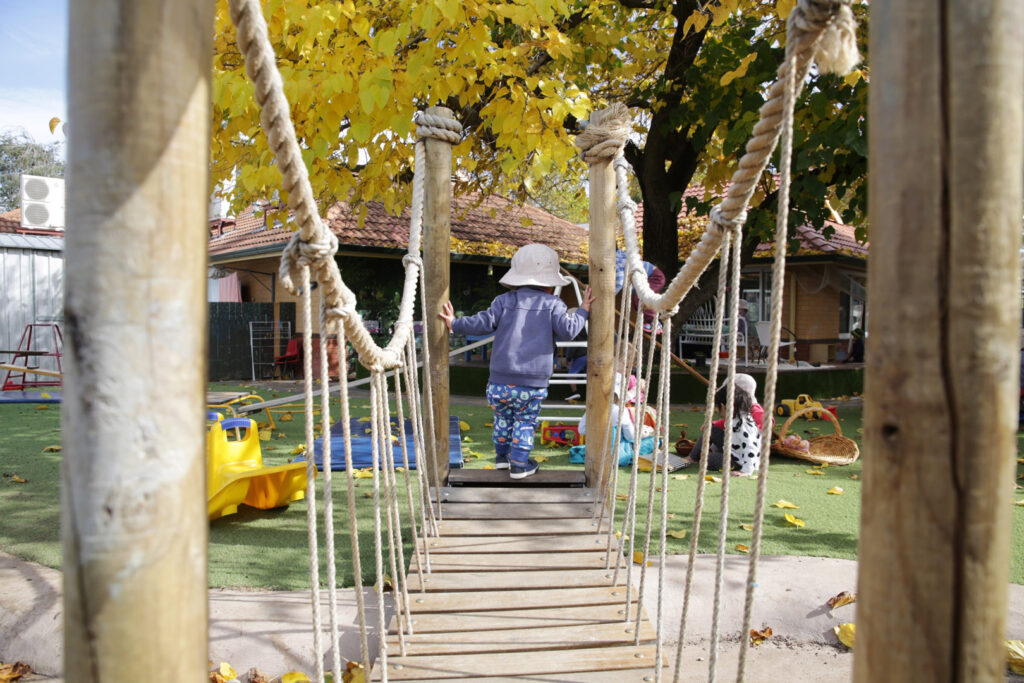 Child walking on a rope bridge at KU Braddon childcare