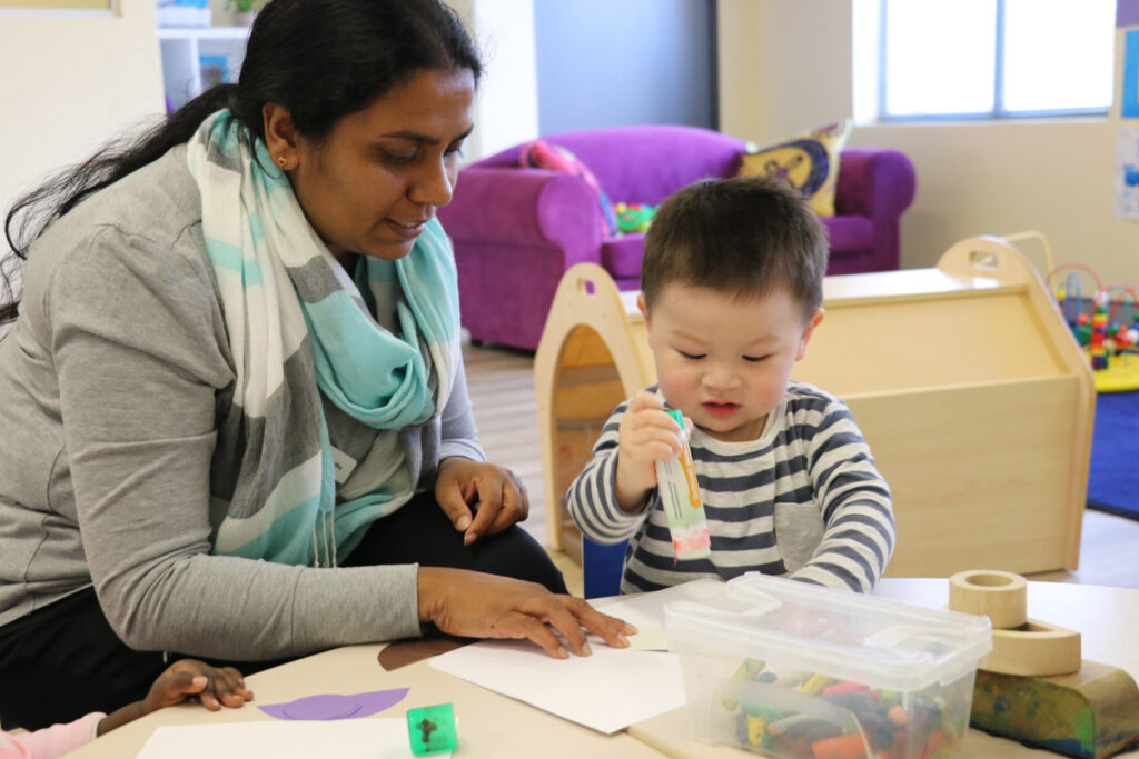 KU Canberra City AMEP childcare educator doing some arts and craft with a child