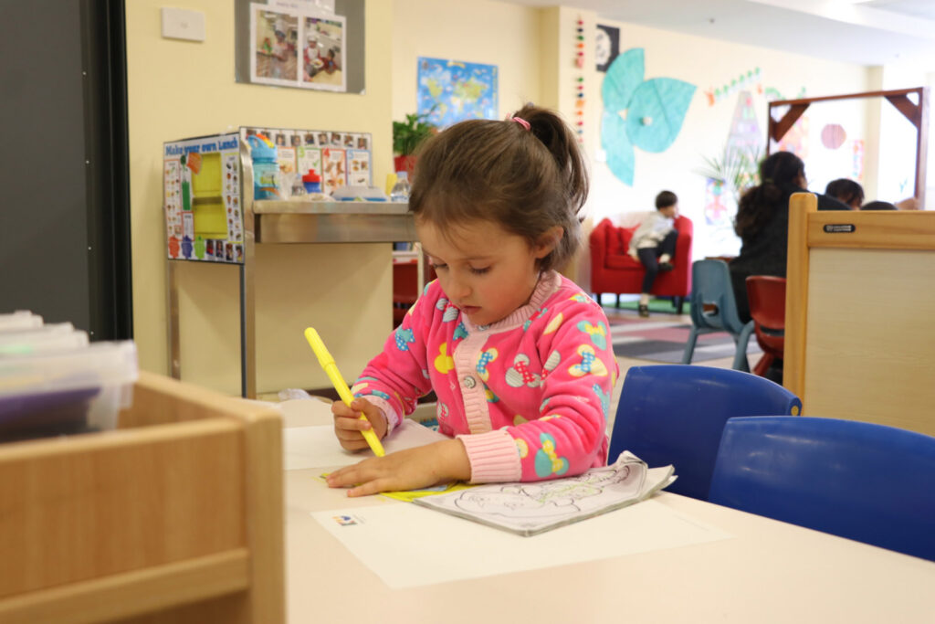 Child colouring a picture at KU Canberra City AMEP childcare