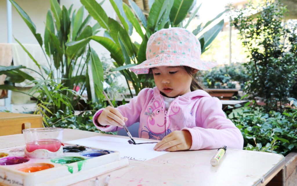 Child painting a picture at KU Castlecrag childcare