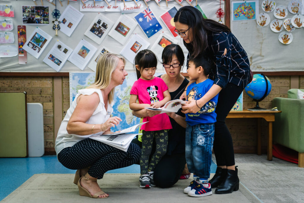 KU Chatswood Community childcare educators reading a book with some children