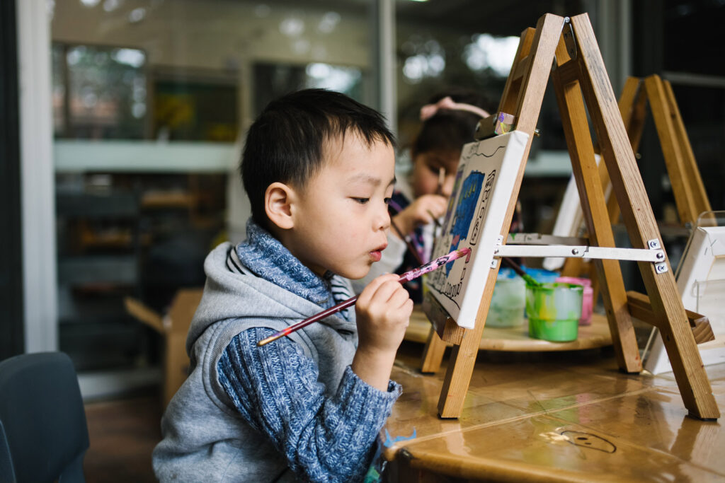 Child doing a painting at KU Cheltenham Memorial childcare