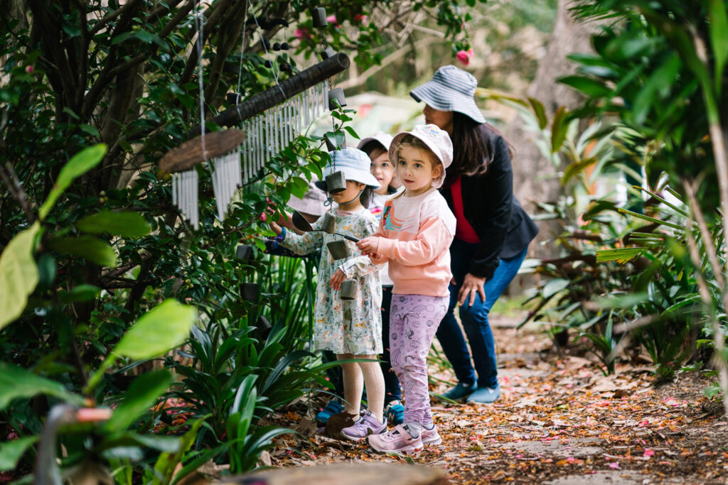 KU Cheltenham Memorial childcare educator with children playing outdoors