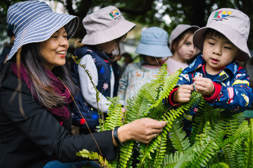 KU Cheltenham Memorial childcare educator with children playing outdoors