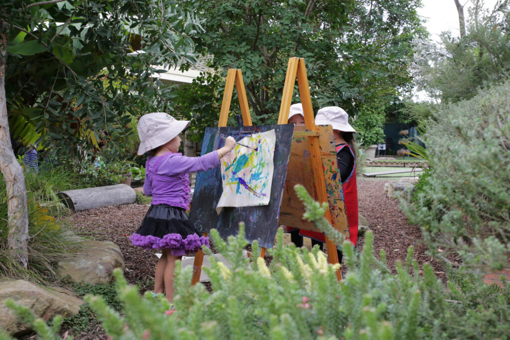 Children painting outdoors at KU Chester Hill childcare