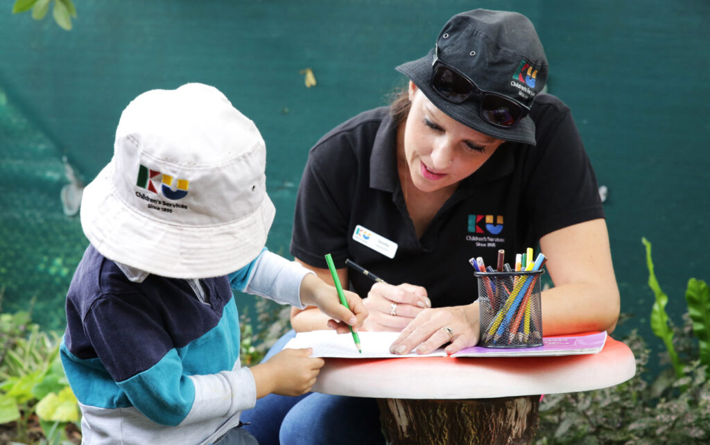 KU Chester Hill childcare educator doing some writing and drawing with a child