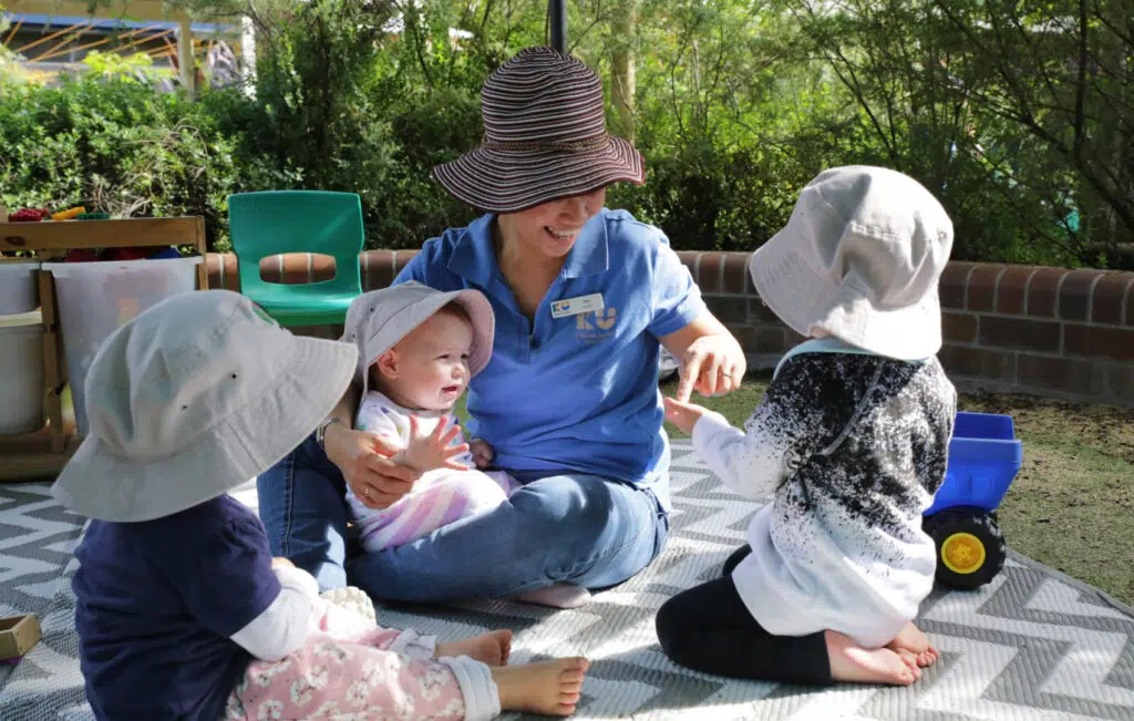 KU Chester Hill childcare educator with some children playing outdoors
