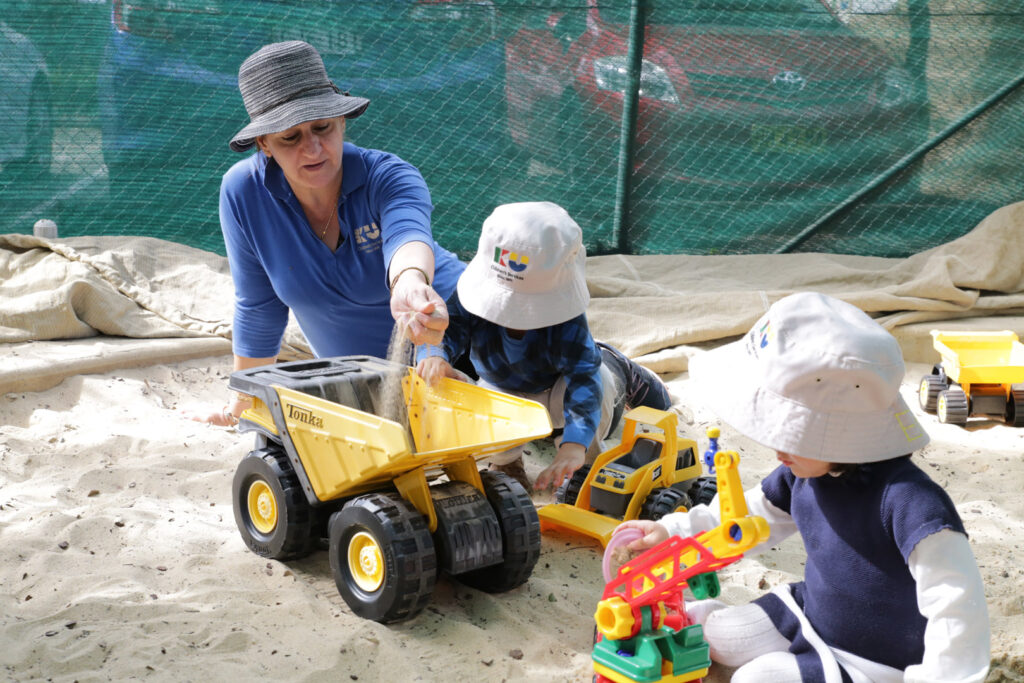 KU Chester Hill childcare educator with some children playing in the sand