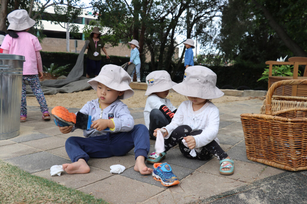 Children cleaning their shoes at KU Eastwood childcare