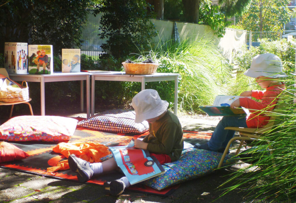 Children reading outdoors at KU Isobel Plus Memorial childcare