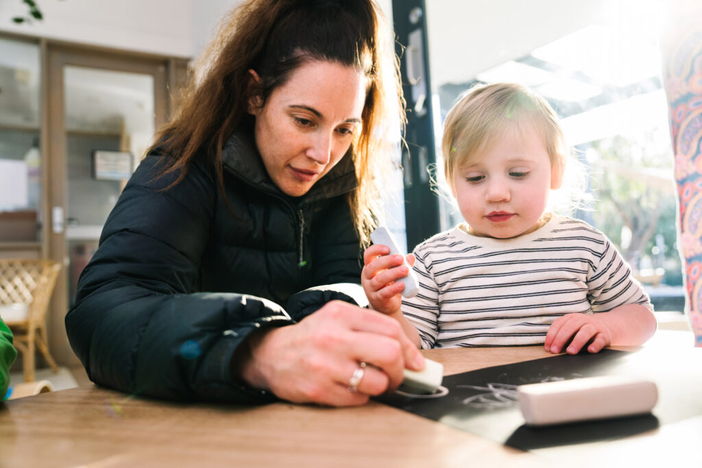 KU Monash childcare educator doing an artwork with a child