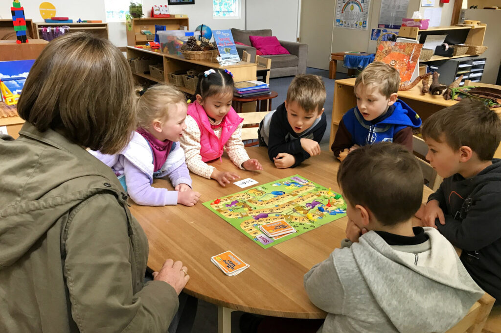 KU Galston childcare educator supervising children playing a board game