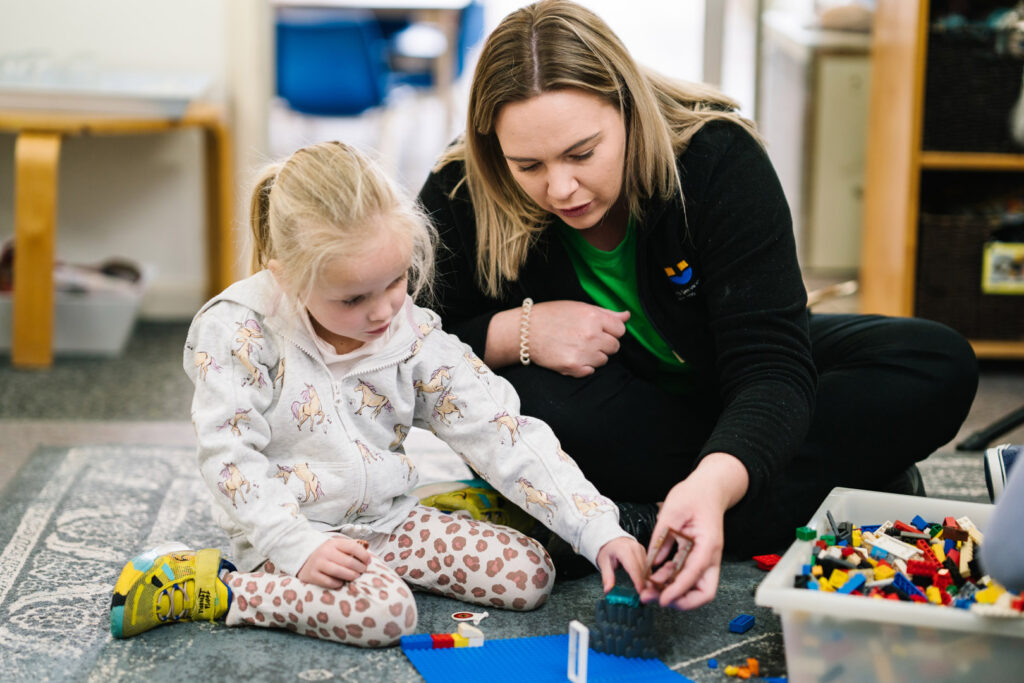 KU Gwynneville childcare educator and a child building with Lego