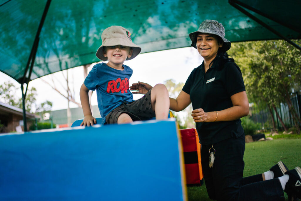 KU Hebersham childcare educator assisting a child on some equipment