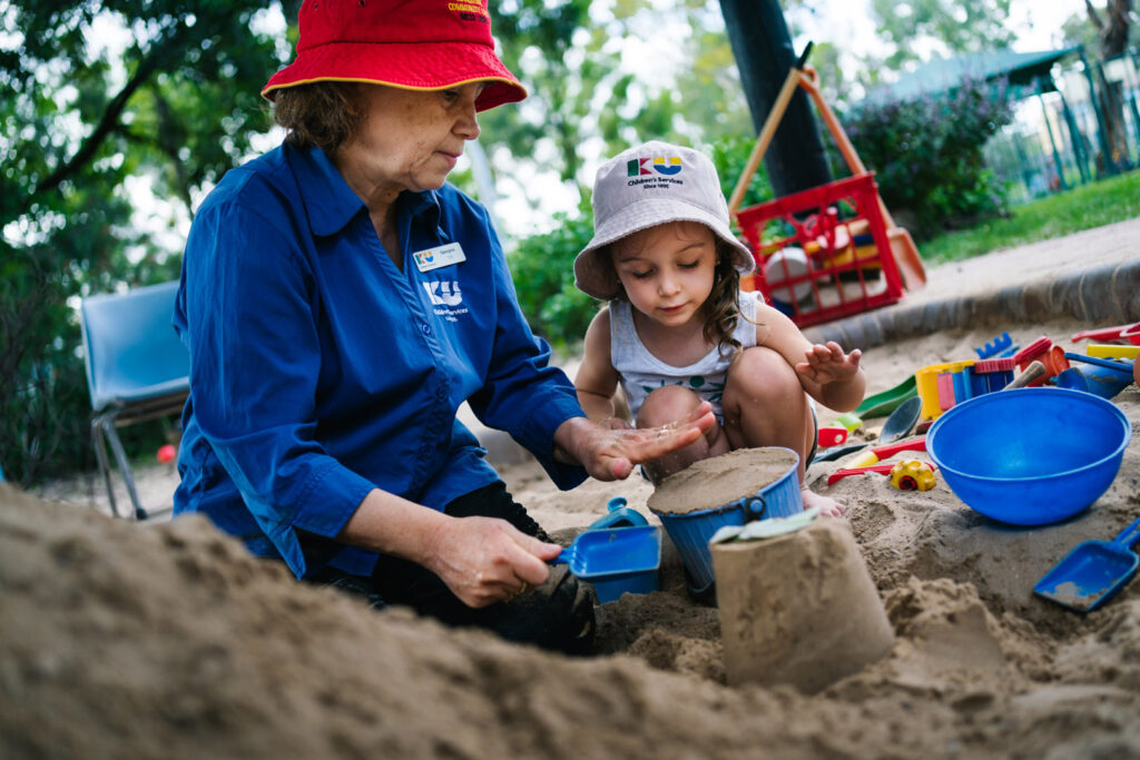 KU Hebersham childcare educator building sandcastles with a child