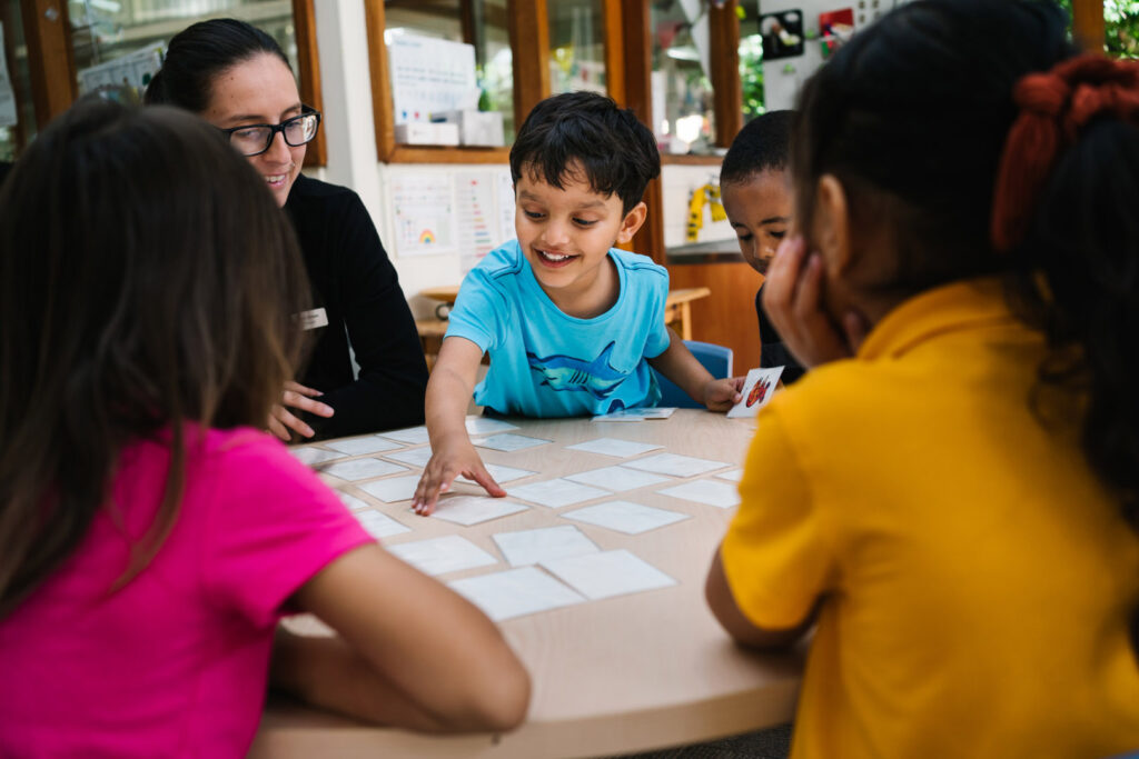 KU Hebersham childcare educator supervising children playing a card game