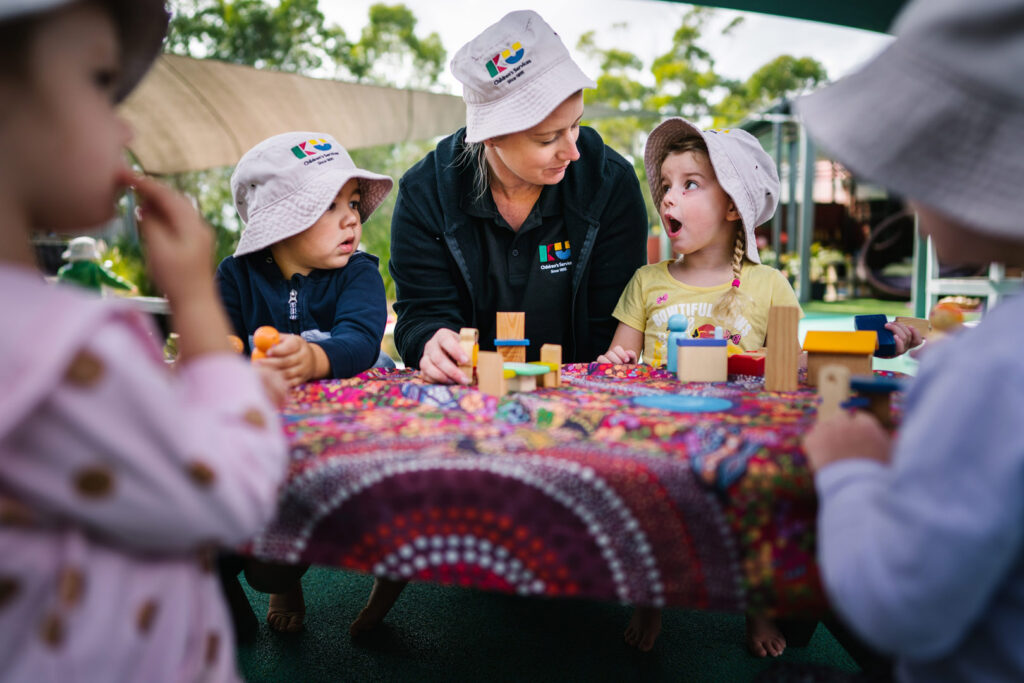 KU Kahibah Road childcare educator and children stacking blocks