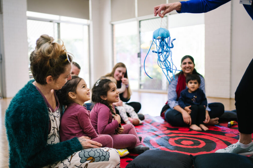 KU NSP Maryland Public School childcare educators sitting in a circle with children looking at a jellyfish