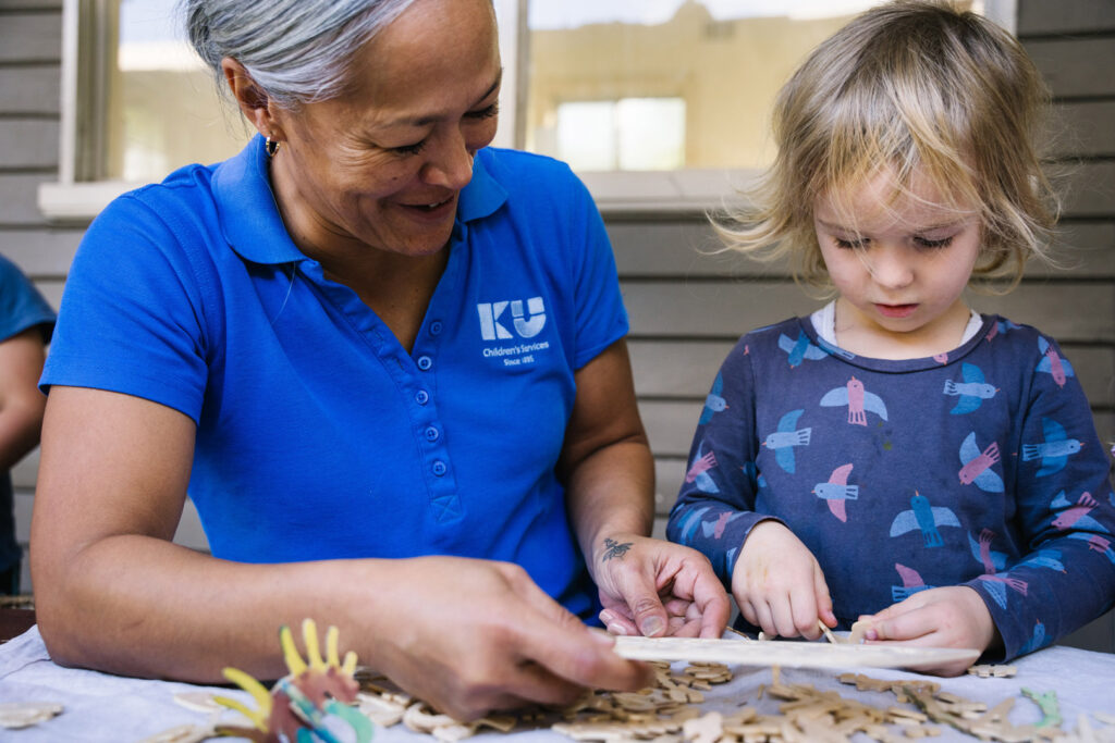 KU Mayfield childcare educator and a child doing some arts and craft