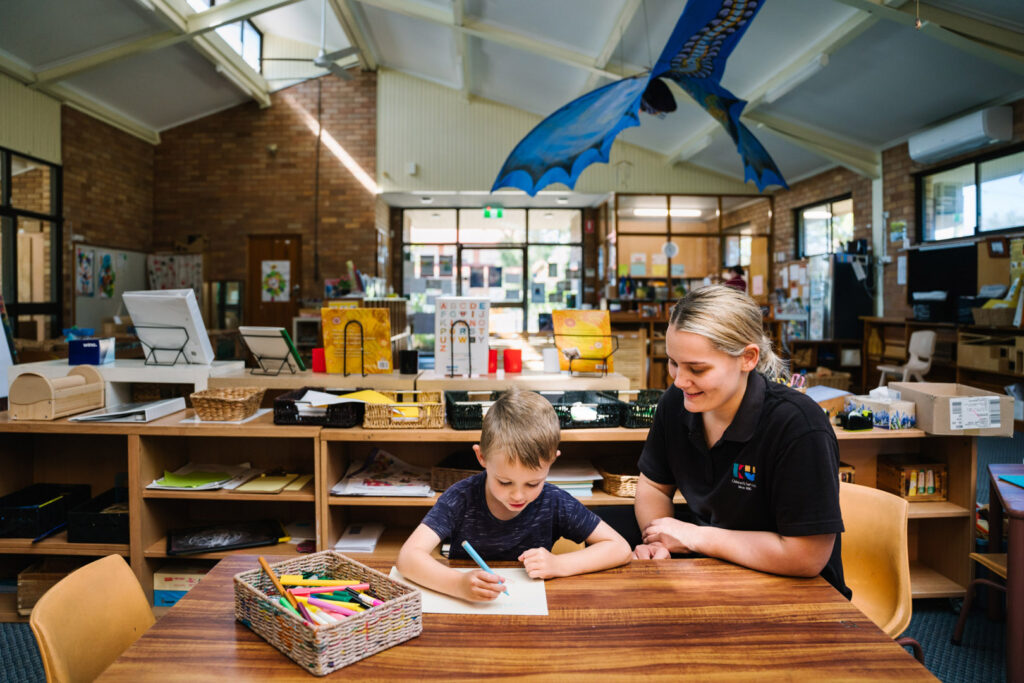 KU Merewether childcare educator and a child doing some writing