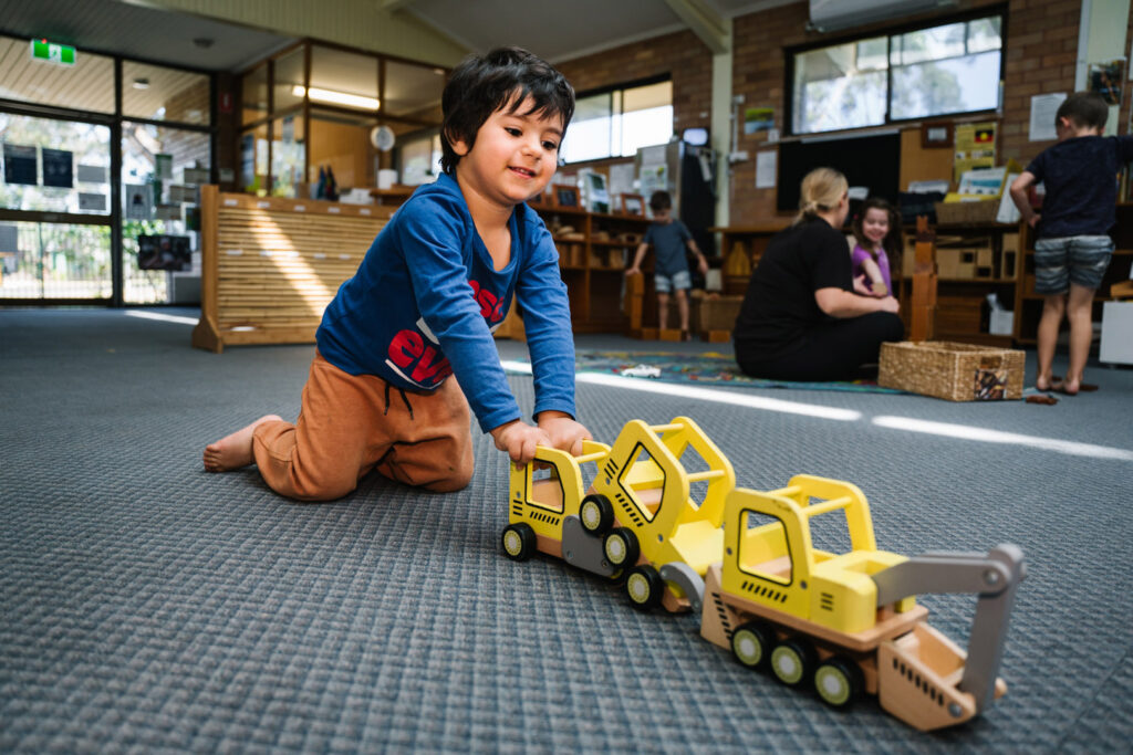 Child playing with a toy digger at KU Merewether childcare