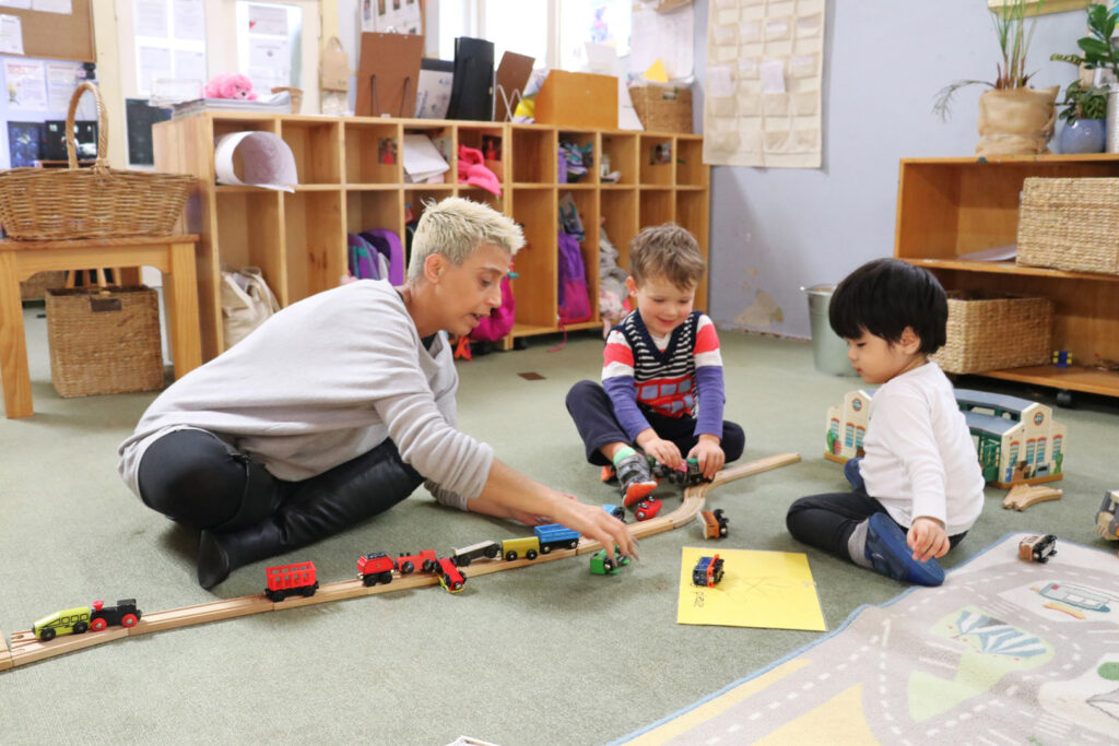 KU Mosman childcare educator and children playing with train sets