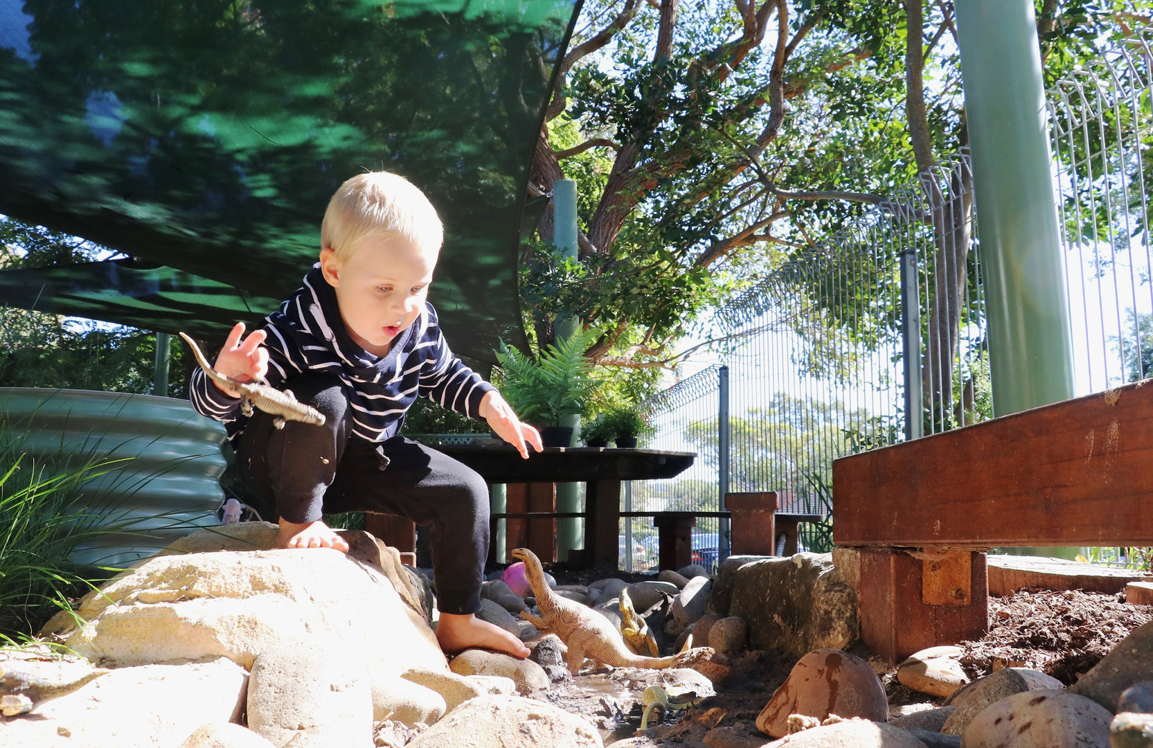 Child playing with dinosaurs at KU Newport childcare