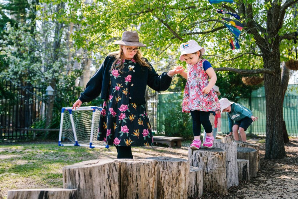 KU Bilya Gulyangarri childcare educator with a child playing outdoors