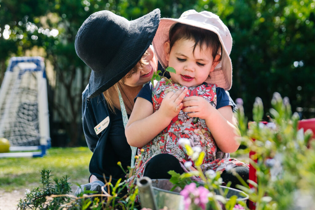 KU Bilya Gulyangarri childcare educator with a child in the herb garden