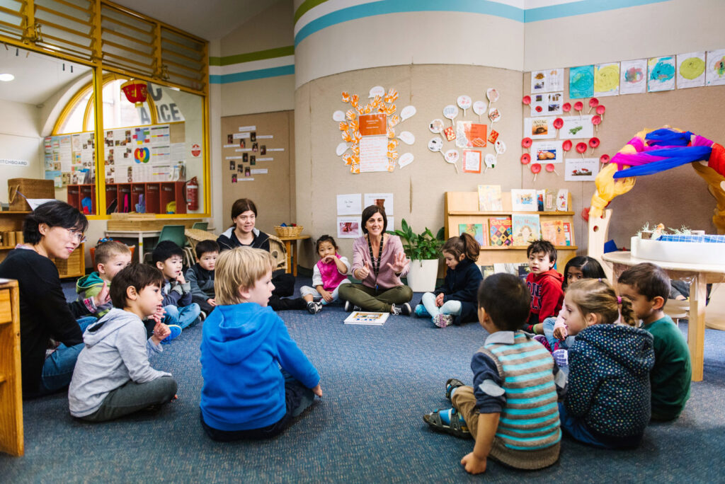 KU Grandstand childcare educators and children sitting in a circle