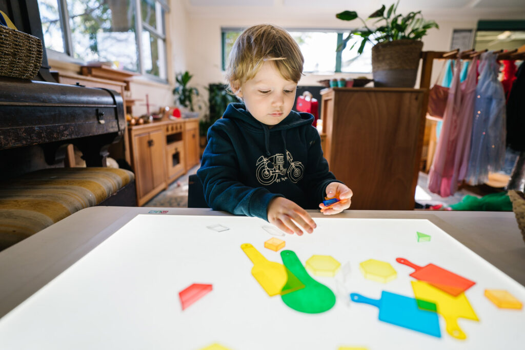 Child playing with translucent shapes at KU Peter Pan Paddington childcare