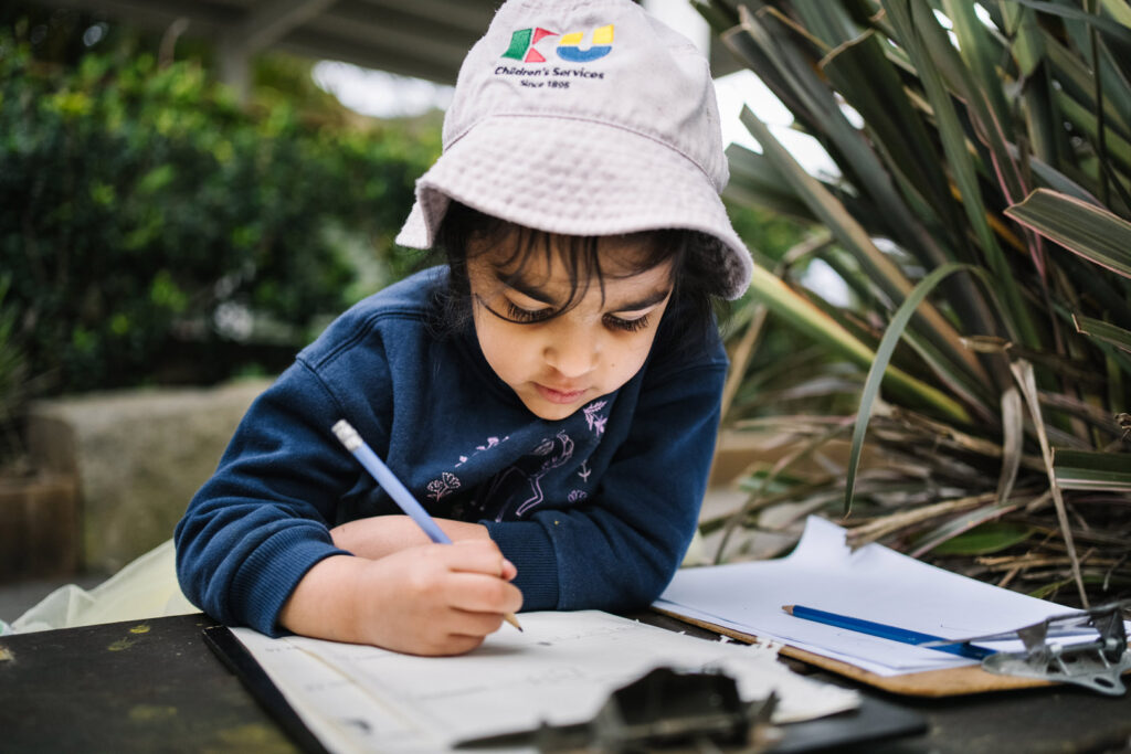 Child doing some writing at KU The Chase childcare