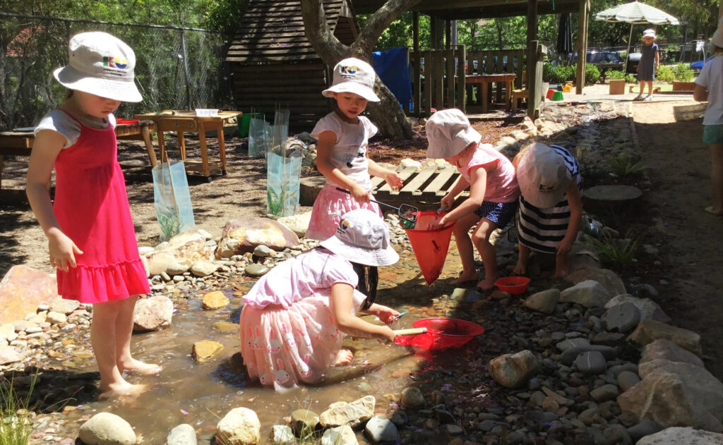 Children playing in the water at KU South Turramura childcare