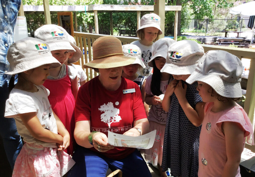 KU South Turramura childcare educator reading to children outdoors