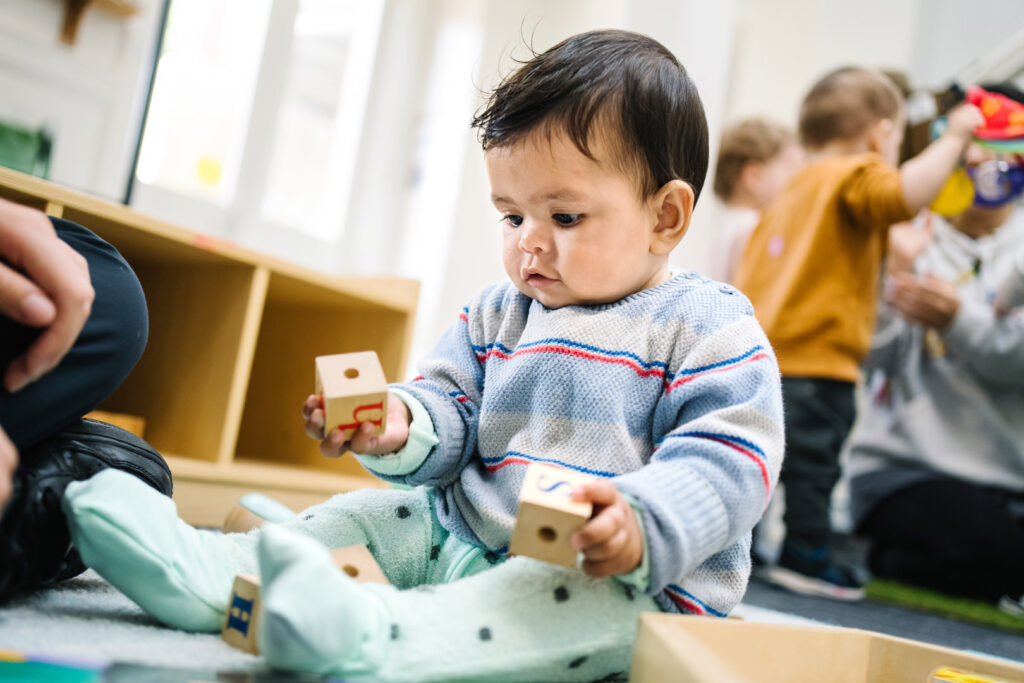 Child holding wooden blocks at KU Ultimo childcare