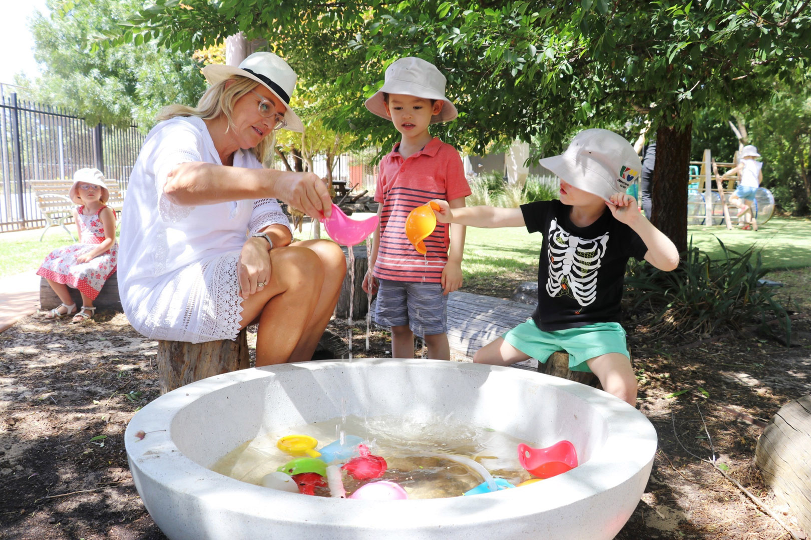 KU Koala childcare educator and children playing with water