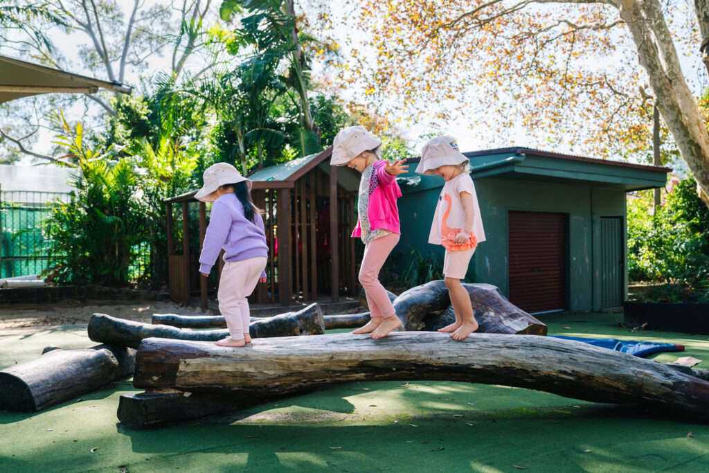 Children balancing on a log at KU James Cahill childcare