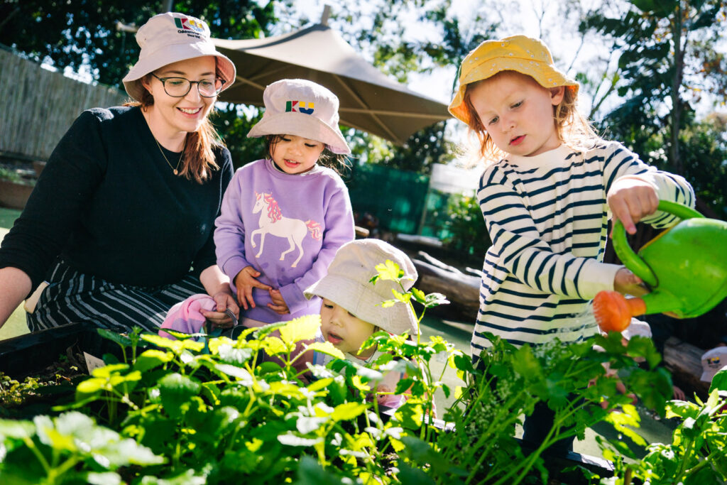 KU James Cahill childcare educator and children watering a garden