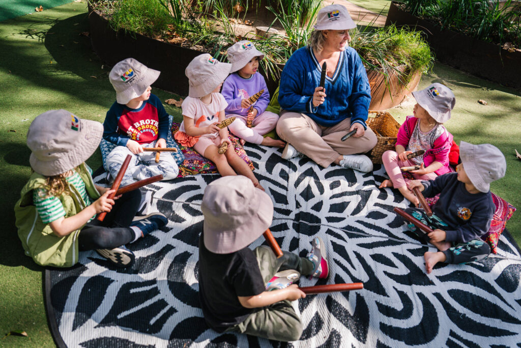 KU James Cahill childcare educator and children sitting in a circle singing a song