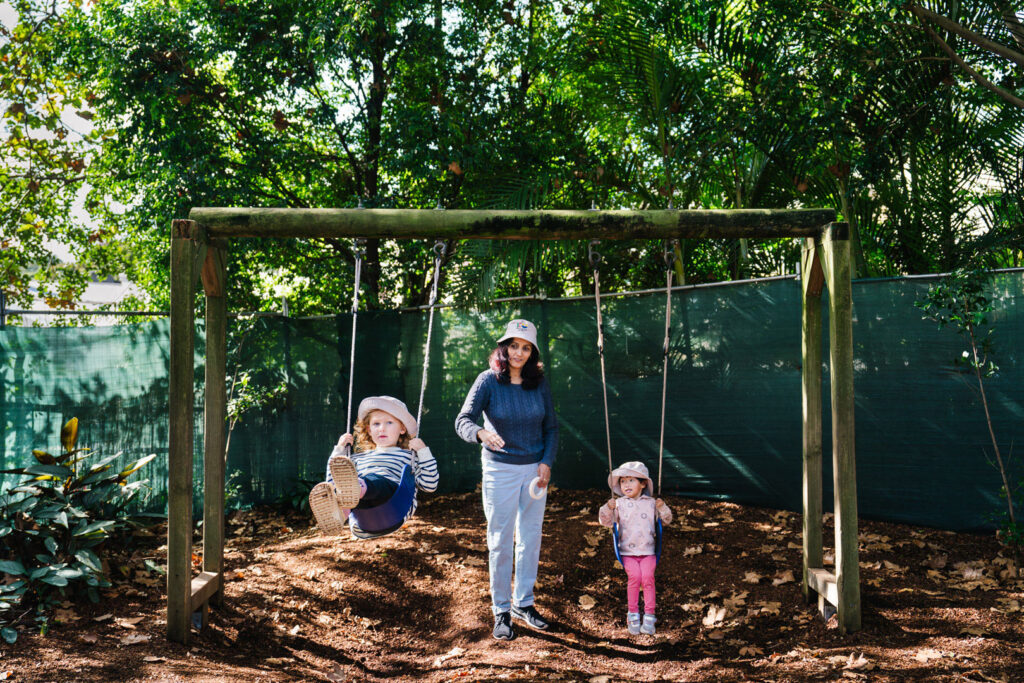 KU James Cahill childcare educator pushing children on the swings