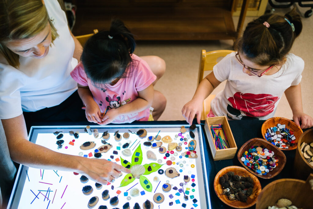 Children playing with objects on a lightbox at KU Bradfield Park childcare