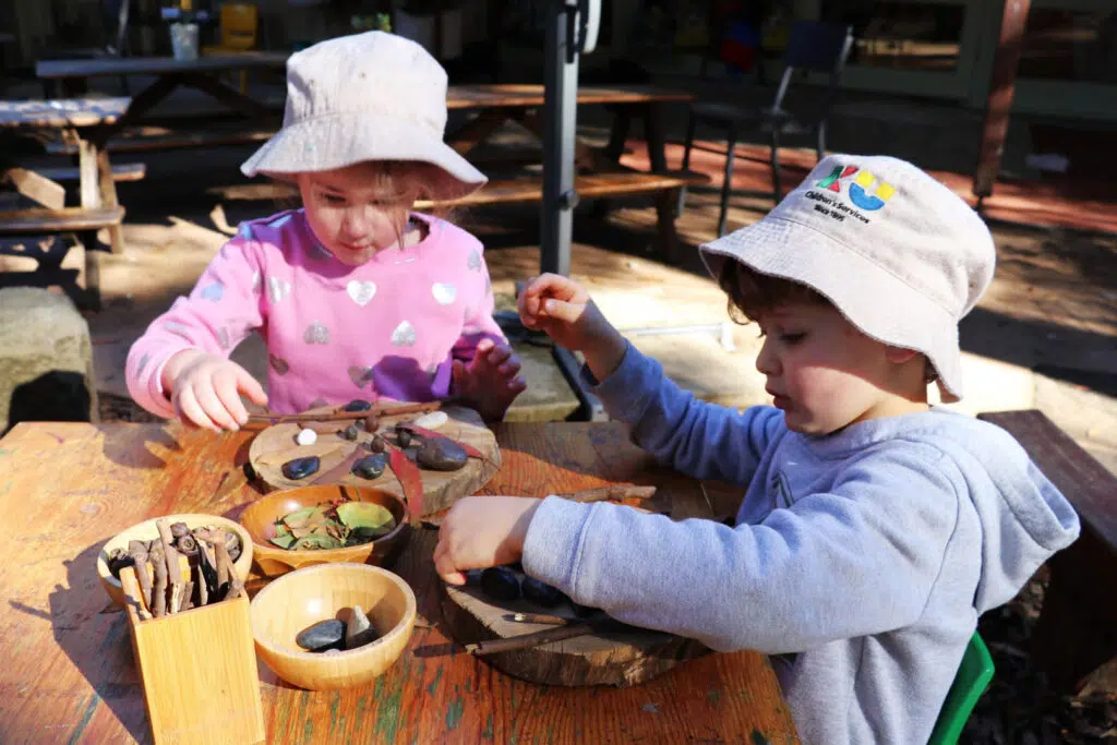 Children playing with sticks and stones at KU West Pymble childcare