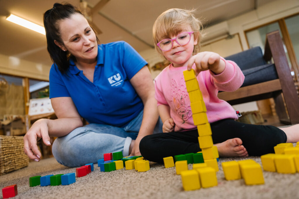 KU Windale childcare educator and a child building blocks